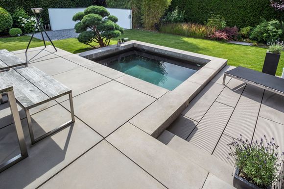 Hochwertige Bodenplatten aus Beton und Wasser bilden im Garten eine optisch reizvolle Kombination.