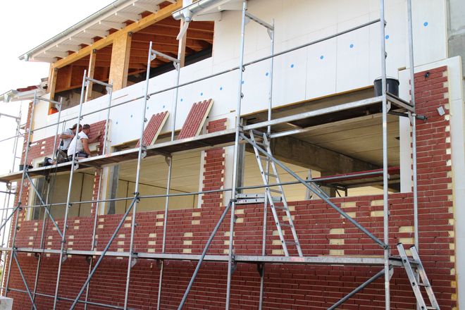 Die Plattenelemente für die Klinkerfassade werden auf der Baustelle an die Wand geschraubt.