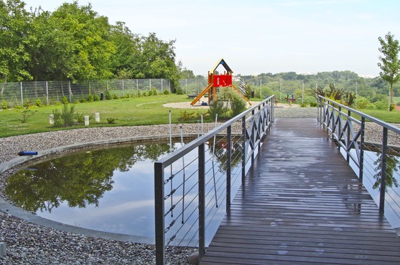 Ein Teich mit Brücke, ein Spielplatz, Sitzgelegenheiten und sogar Bäume - all das lässt sich auf einem Flachdach realisieren. Diese Begrünung fand auf einer Tiefgarage statt und spendet den Anwohnern einen grünen Rückzugsraum.
