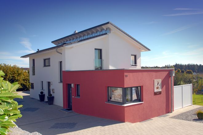 Vorausschauend geplant wurde dieses Einfamilienhaus in Ziegelbauweise. Der flache Anbau in Rot besitzt einen separaten Eingang und beherbergt Gewerberäume, die auch als Homeoffice genutzt werden können.