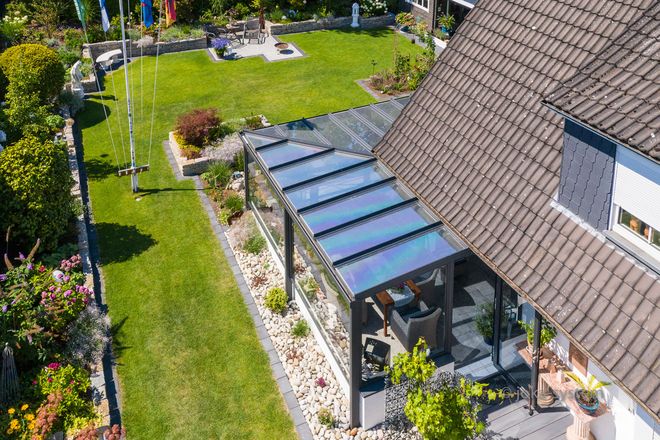 Der Glasvorbau schützt vor Regen und kühlen Temperaturen - und lässt sich bei schönem Wetter ganz einfach öffnen.