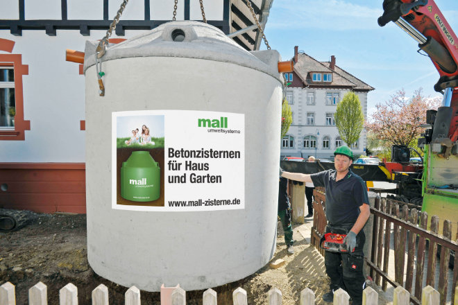 Eine Zisterne wird in die vorbereitete Baugrube gehoben.