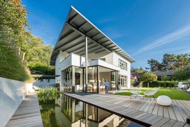 Das modernisierte Eigenheim von Familie Neumann: Der Teich mit Holzummantelung, das imposante Dach und der gläserne Anbau mit der Glas-Faltwand verleihen ihm eine unverwechselbare Optik.