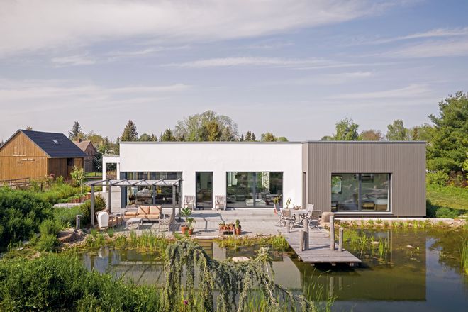Die Fassade des freigeplanten Bungalows mit Gartenteich von Familie Ulrich ist teilweise mit Holz verkleidet, um das Haus der ländlichen Umgebung anzupassen.