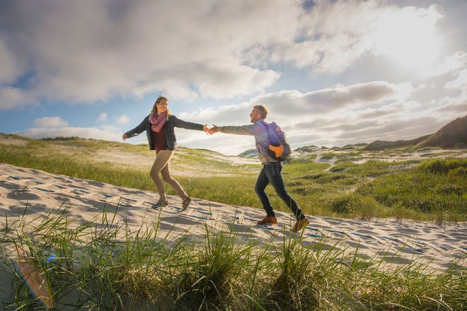 Eine steife Brise weht den Gästen bei einer herbstlichen Dünenwanderung um die Nase.