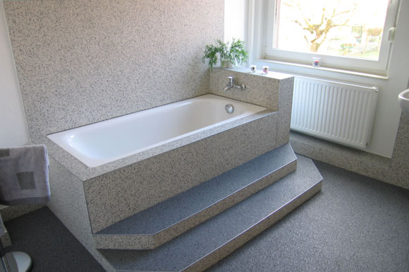 Natursteinteppiche eignen sich nicht nur als frischer Bodenbelag fürs Bad. Auch Wände oder die Einfassung der Badewanne lassen sich damit stilvoll und individuell realisieren.